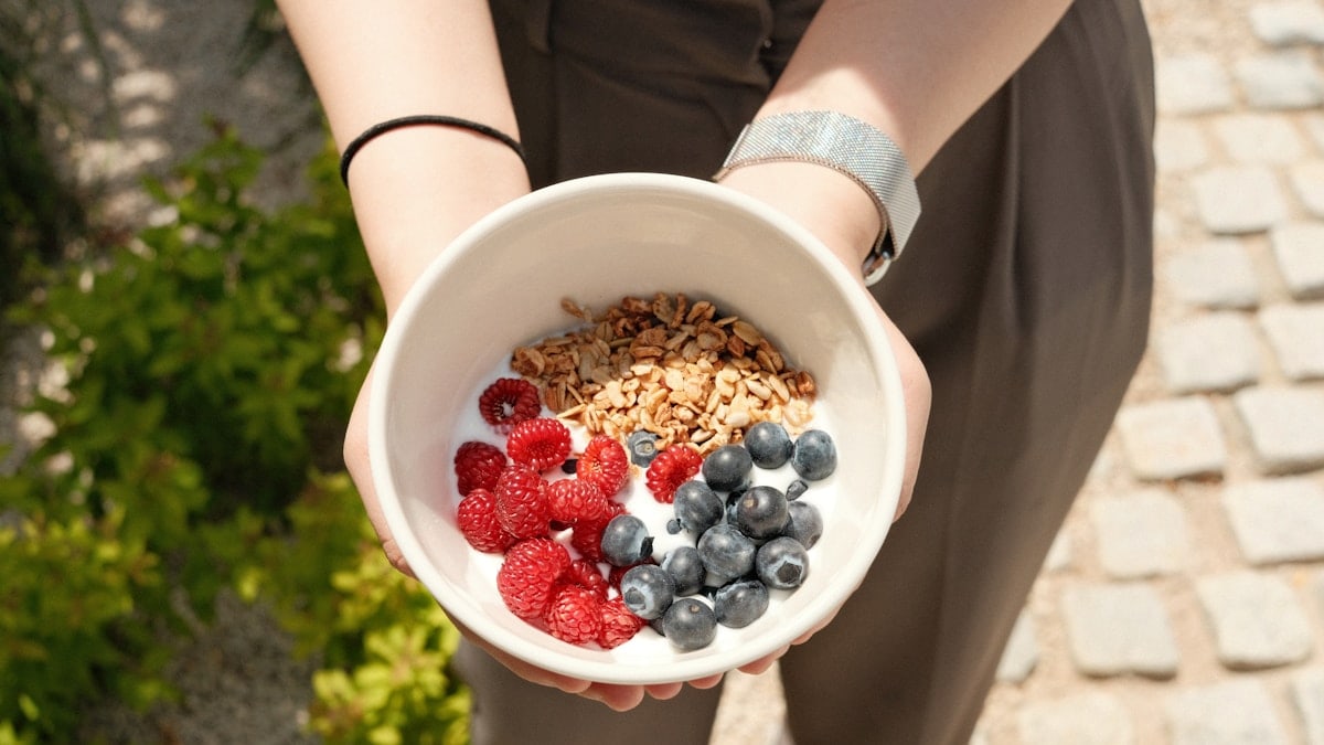 a person holding a bowl of cereal and berries